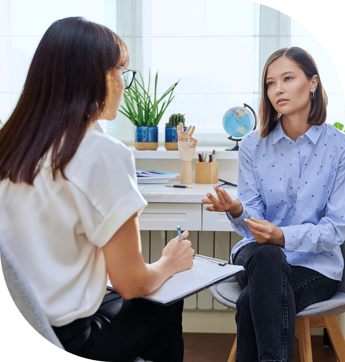Two women engaged in a serious conversation in a bright office.