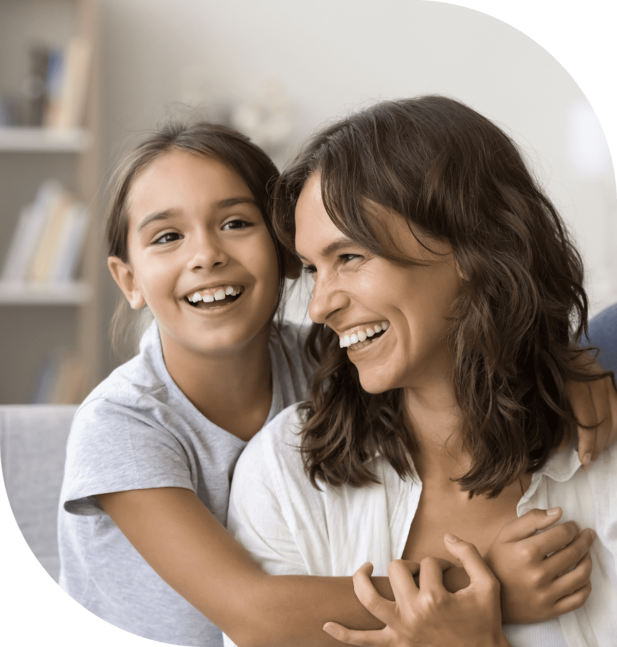 A joyful girl hugs her smiling mother indoors.
