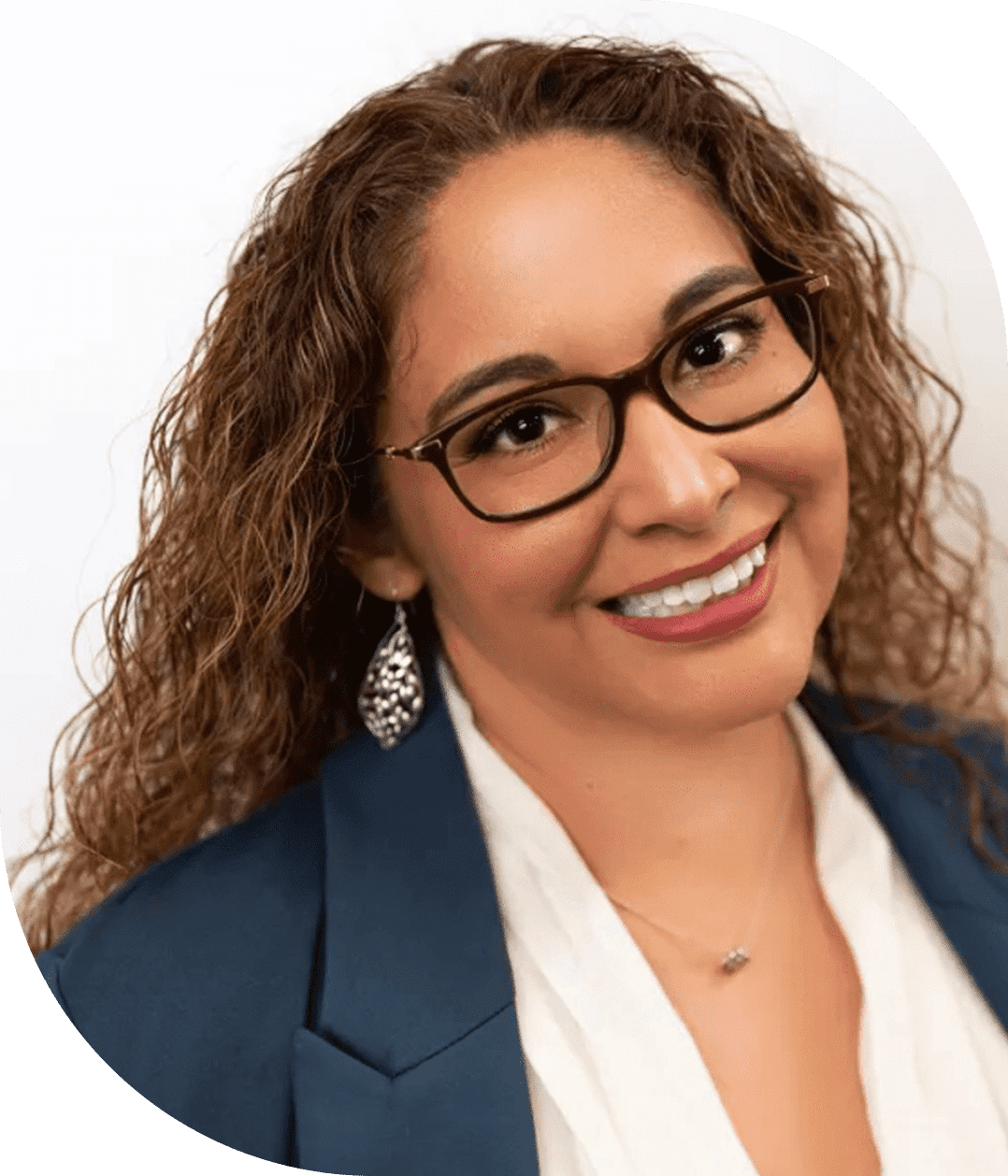 A smiling woman with curly hair and glasses wearing a blue blazer.